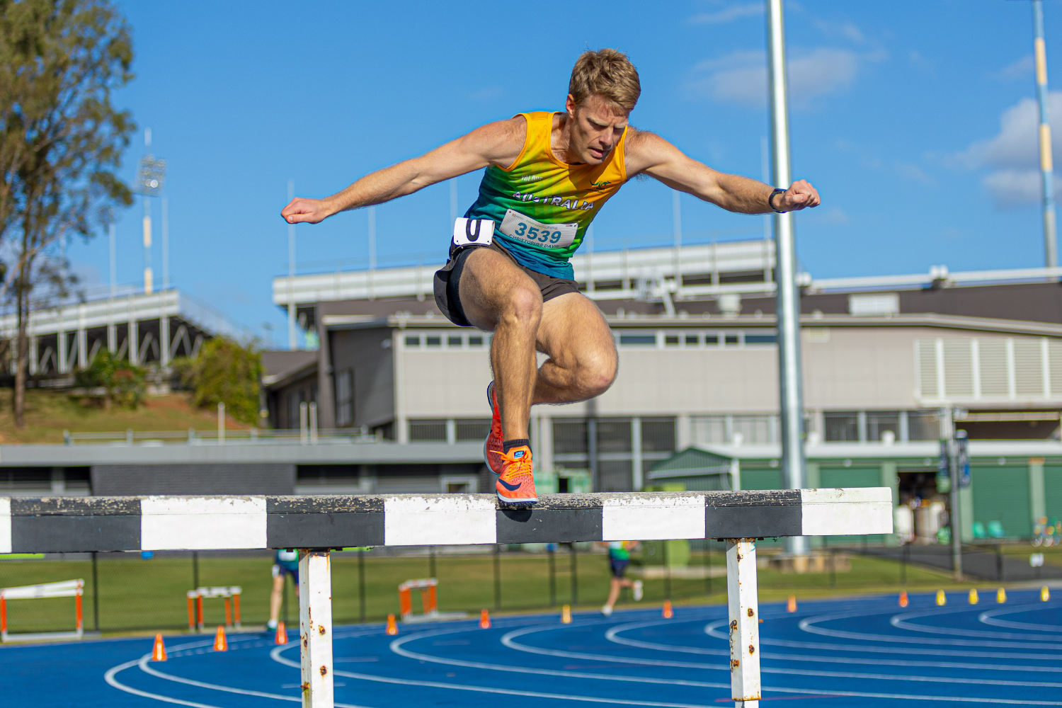 A masters athlete clearing the water jump barrier, landing in the water below