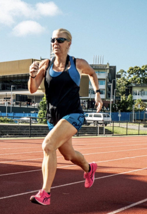 Karen Lakin running on the track in sunglasses and pink shoes