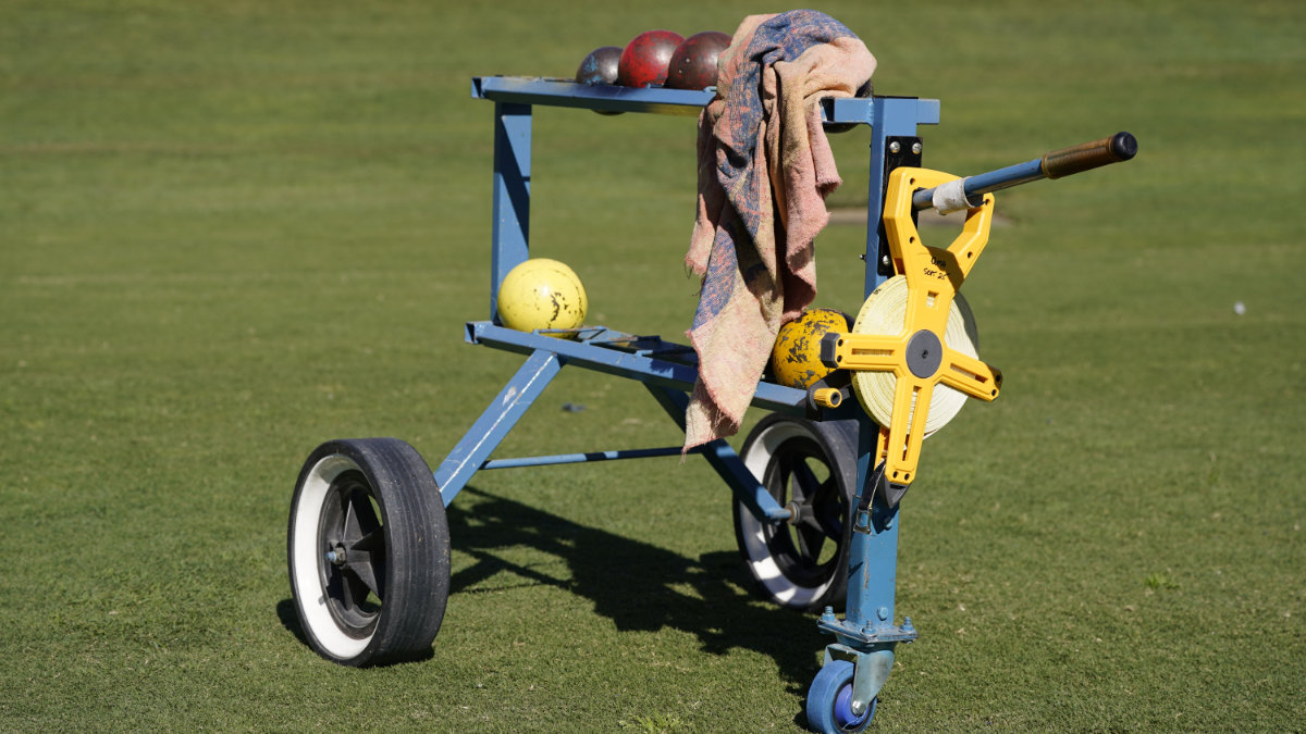 A trolley of shot puts and a measuring tape on the infield grass