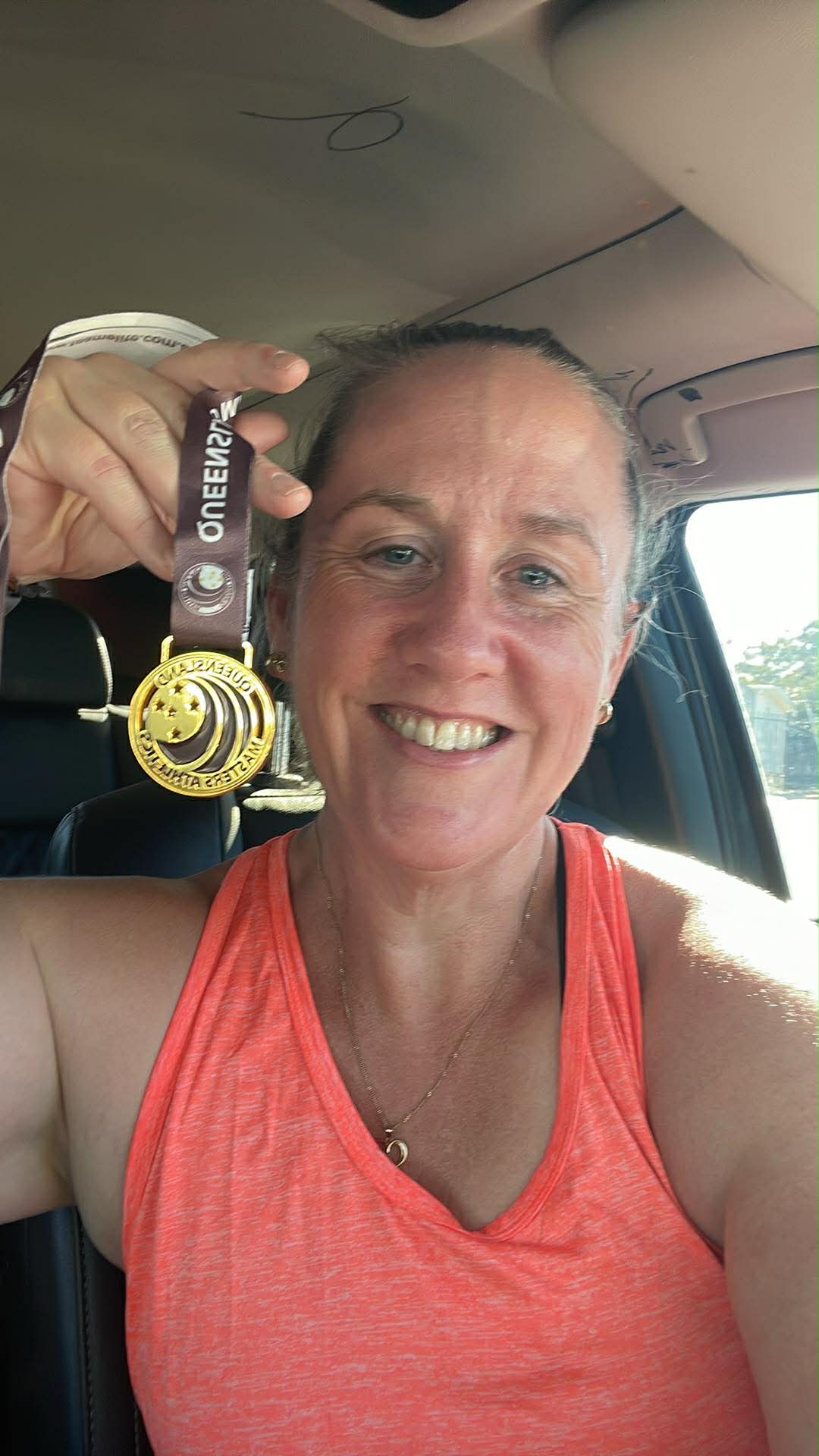 Kath holding up a Queensland Masters Athletics medal