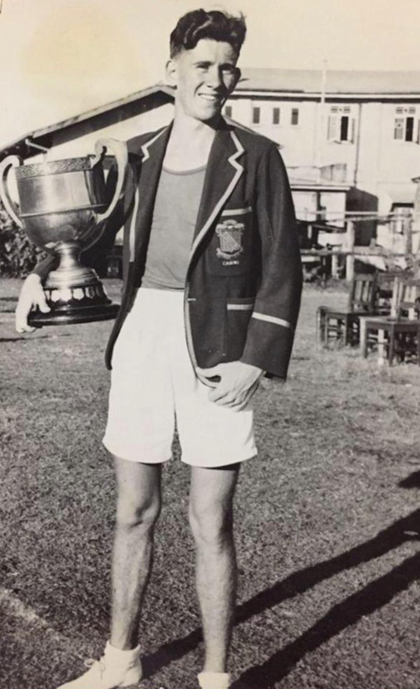 A young Laurence Quinlivan in his school blazer, holding a large trophy cup